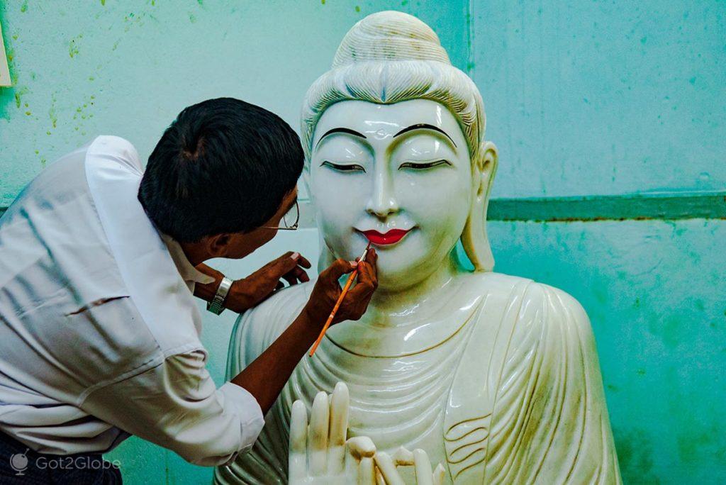 Artesão finaliza uma estátua polida de Buda.