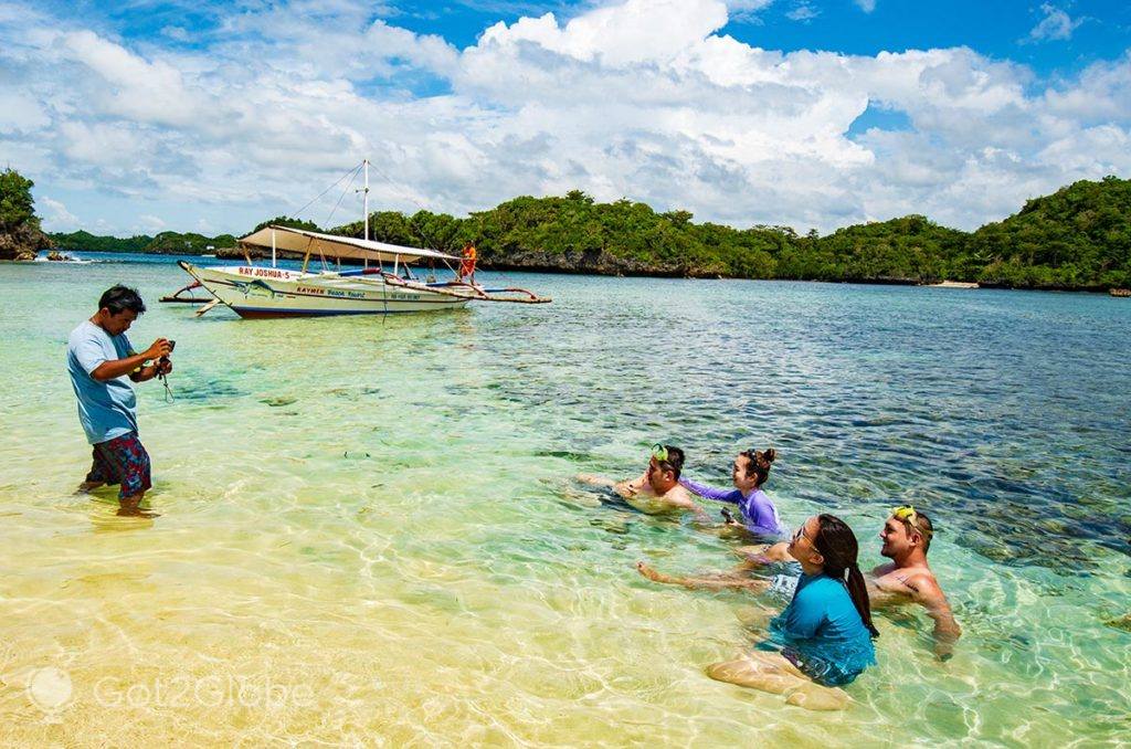 Timoneiro de guia fotografa um grupo de banhistas visitantes de Guimaras e ilha Ave Maria