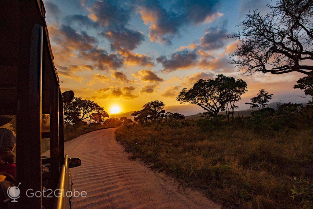 Jipe percorre uma estrada de terra batida do parque, sobre o ocaso.