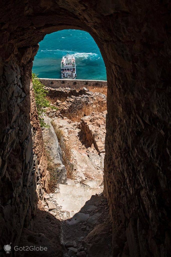 Vista de um barco e do mar em redor através de uma porta da fortaleza de Spinalonga